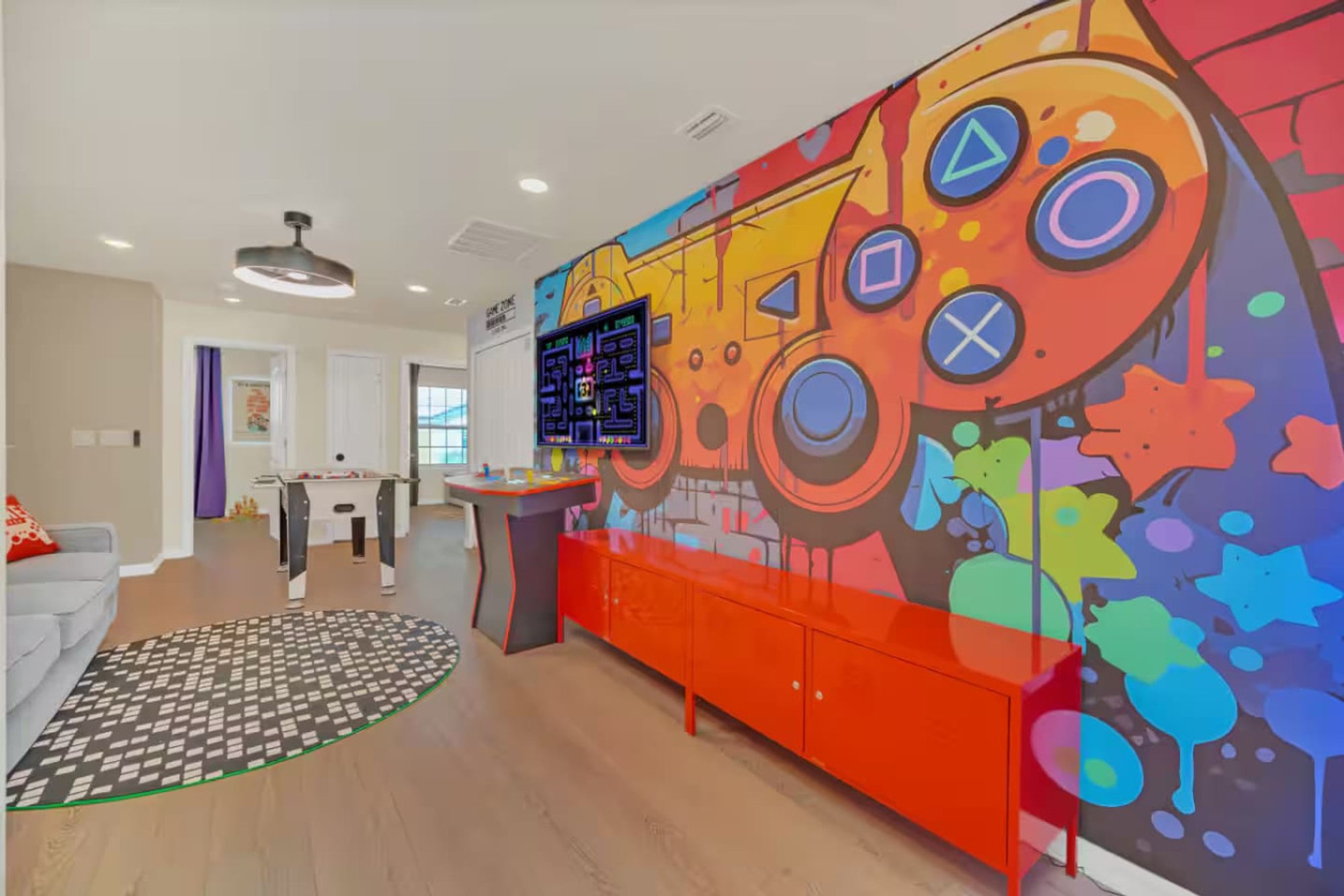 Game loft seen from the landing, with the arcade cabinet and its painted game-controller mural