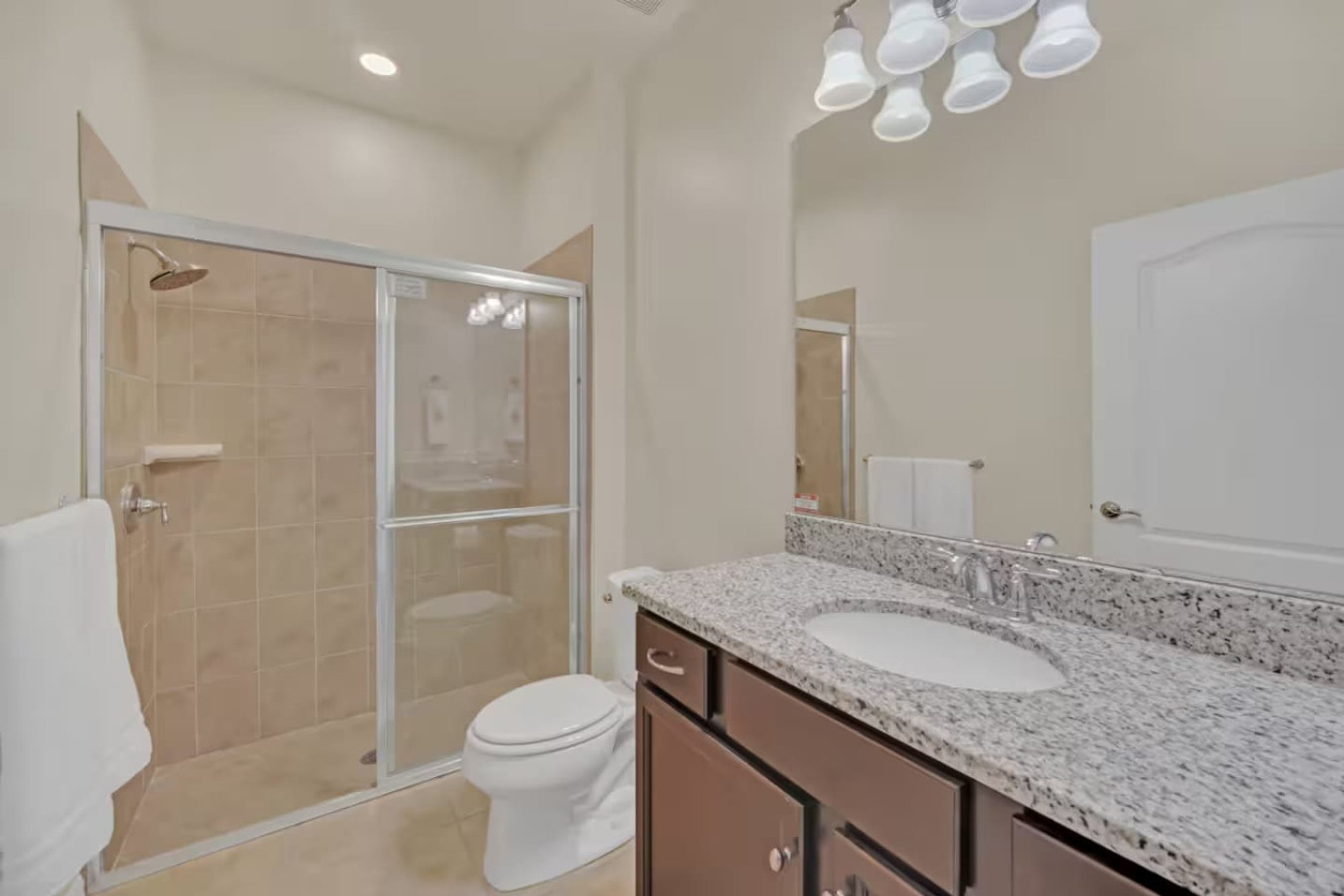 Downstairs full bath with a walk-in shower and granite vanity