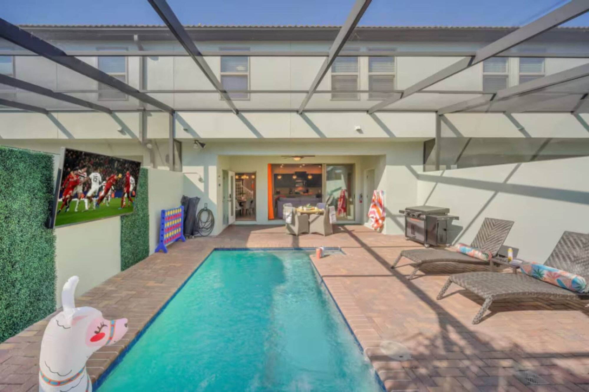Loungers on the pool deck facing the outdoor TV