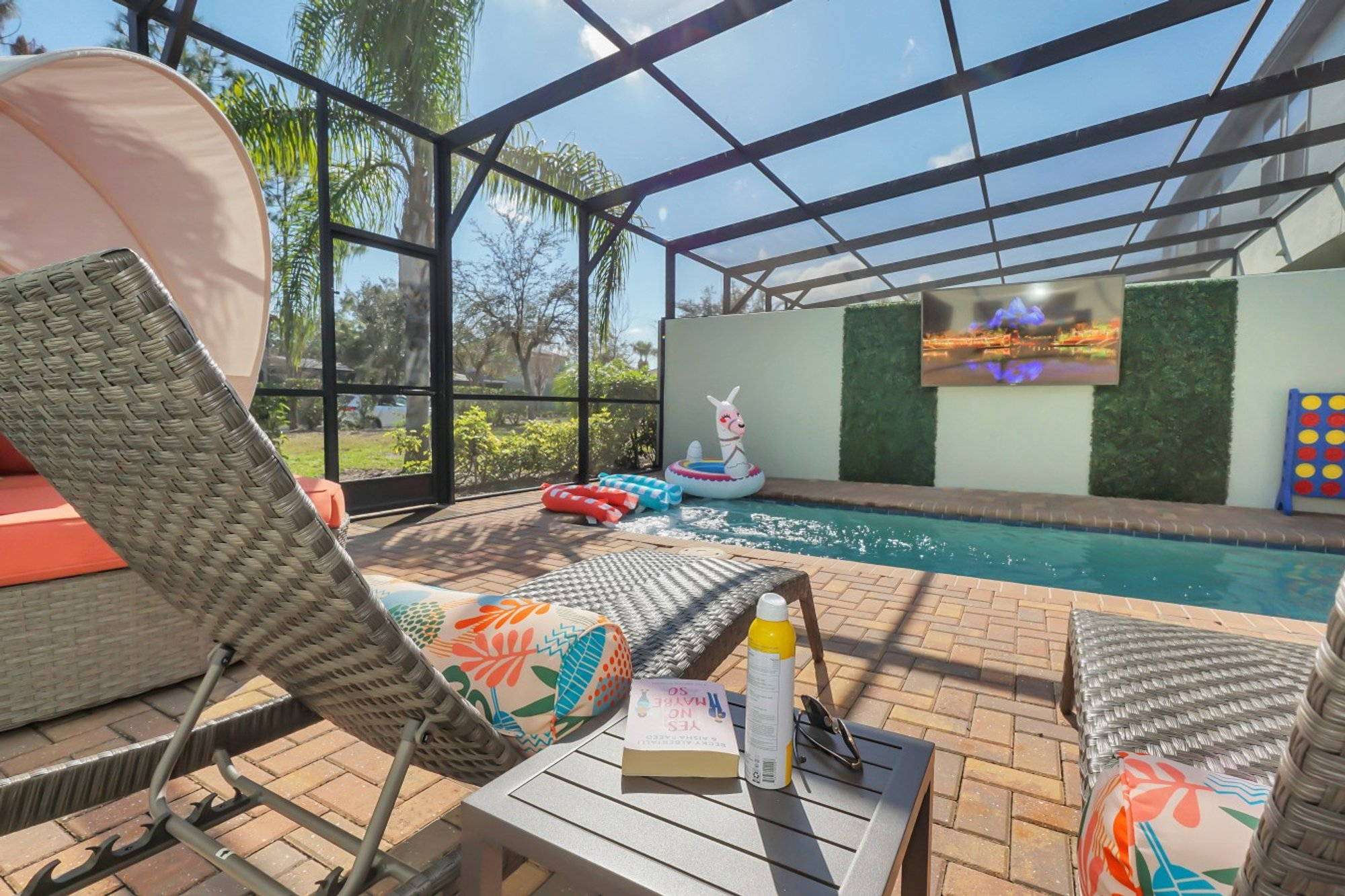 Screened private pool with loungers and the 75-inch outdoor TV on the far wall