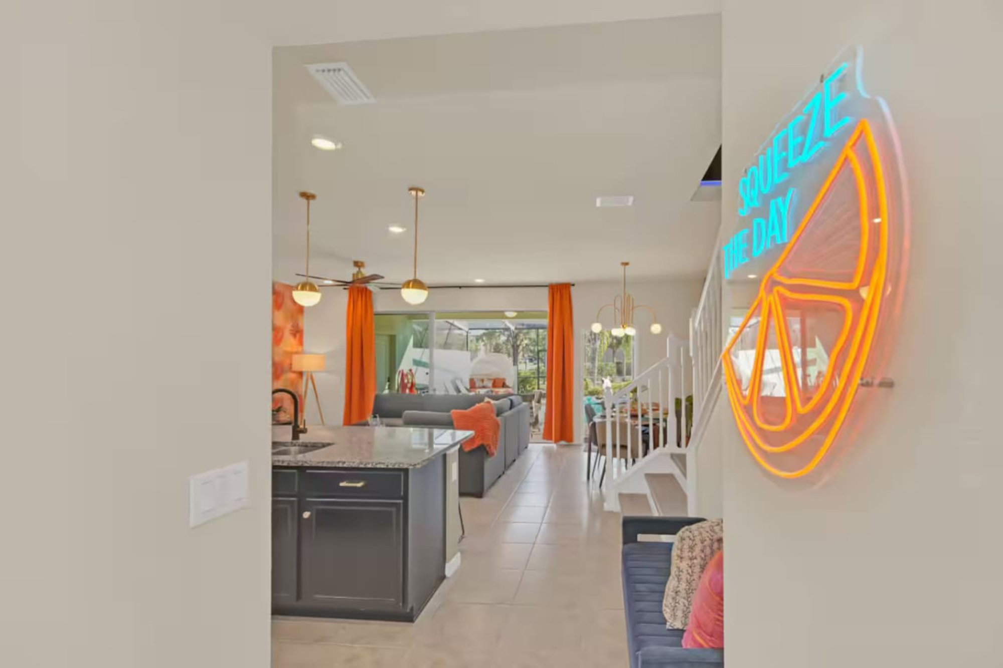 Neon Squeeze the Day orange-slice sign on the wall beside the kitchen