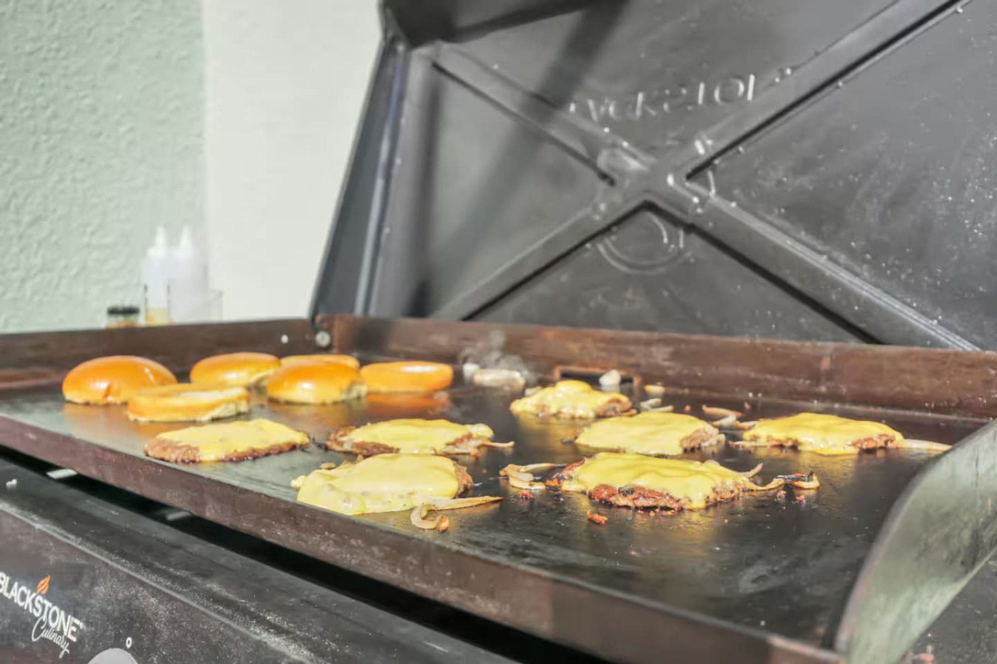 Burgers cooking on the Blackstone griddle by the pool