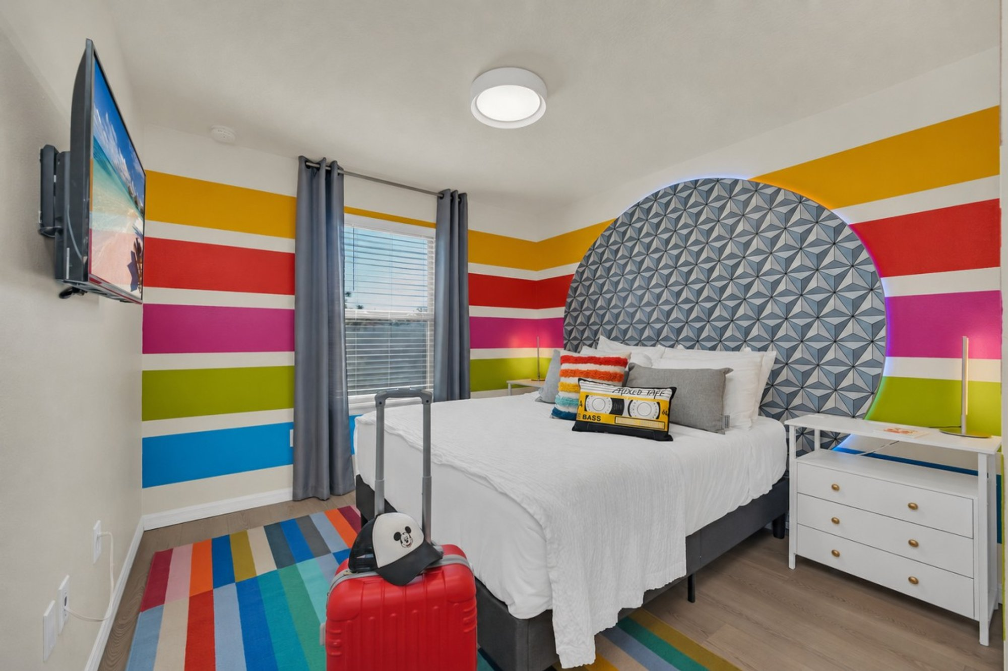 Queen bed in Bedroom 5 against the rainbow striped wall